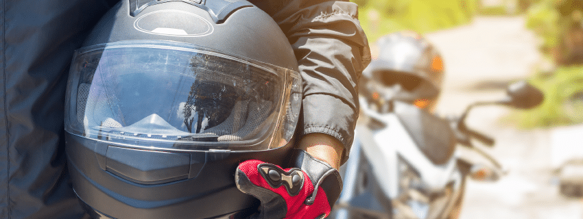 Motorcyclist holding a helmet on his side
