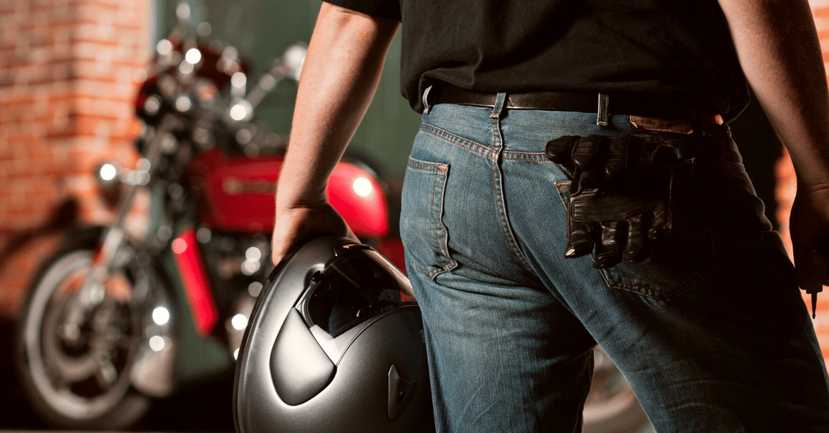 Male biker with helmet on his hand and gloves on his pocket ready to ride his motorcycle