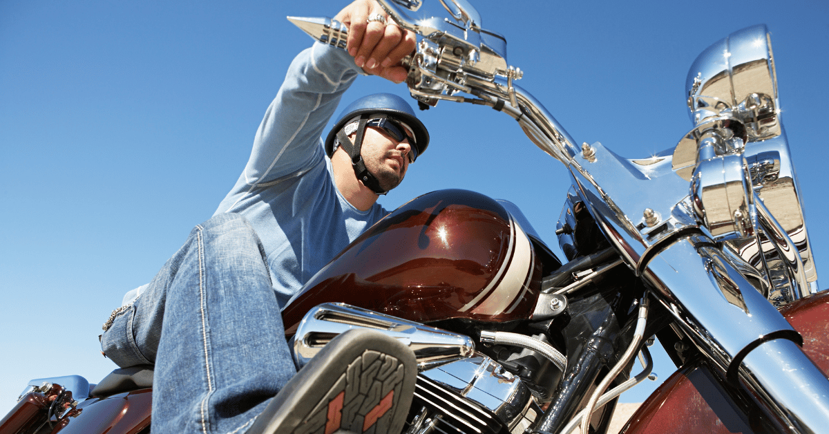Male motorcyclist wearing helmet and glasses riding motorcycle.